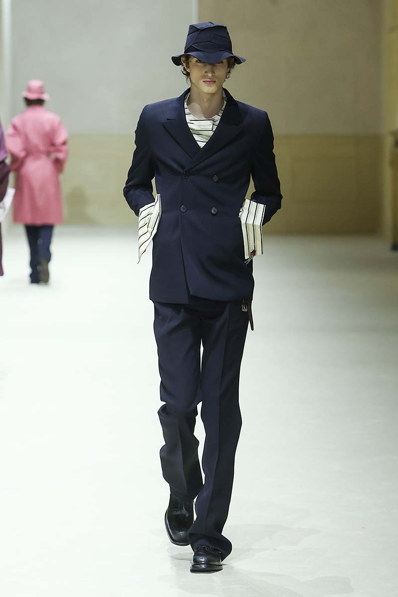 Donkerblauw double-breasted herenpak van Prada met verlengde blazer, overhemd met opvallende manchetten. Photo courtesy of Prada