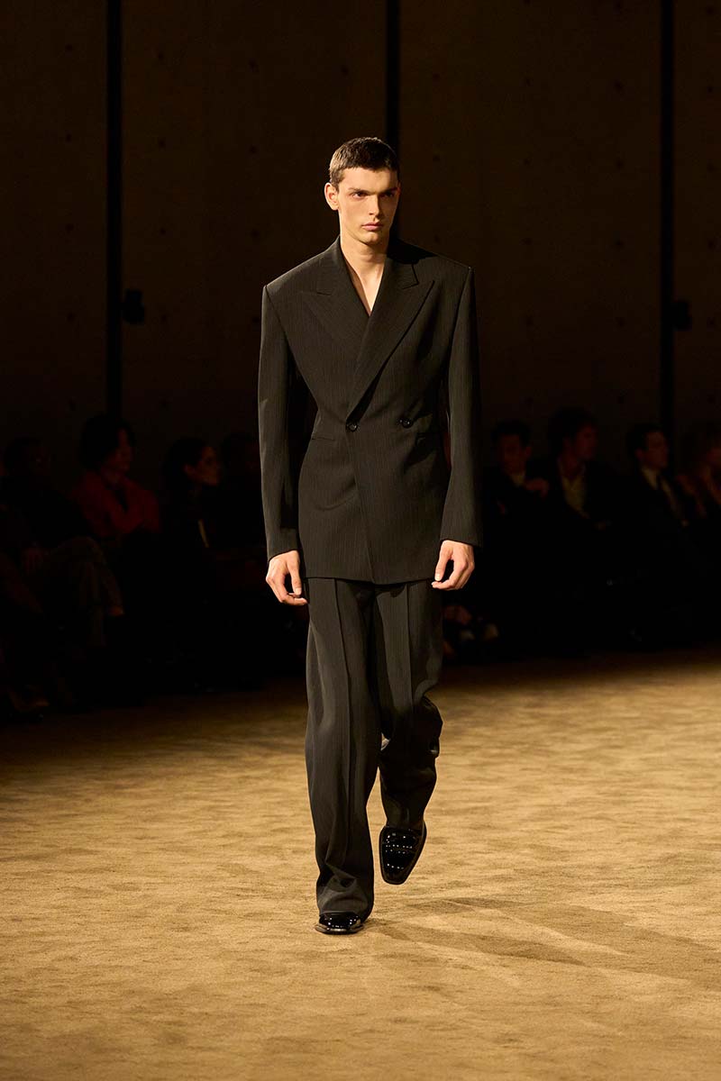 Slank en langgerekt herenpak van Saint Laurent met double-breasted blazer, brede schouders en smalle pantalon. Photo courtesy of Saint Laurent